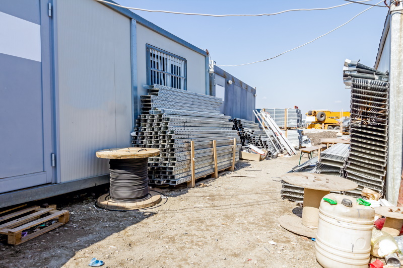 Cable trays and cord spools are stacked among container office is placed at construction site, waiting to be used in new edifice. Crédit : Roman_23203AdobeStock